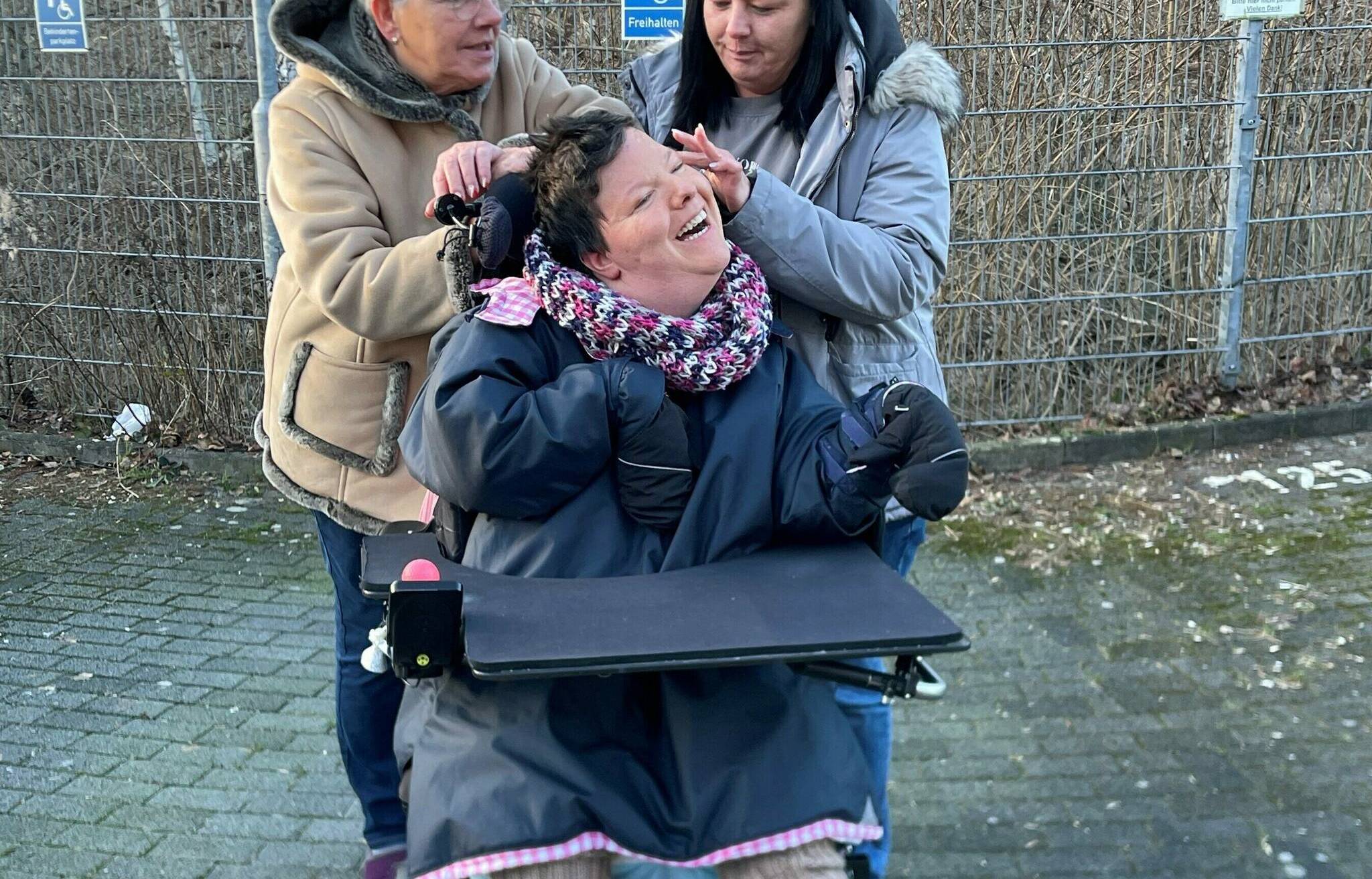 Ilke und Melanie Teubner mit der mehrfachbehinderten Regina vor dem Behindertenparkplatz, wo einst der Transporter stand.  