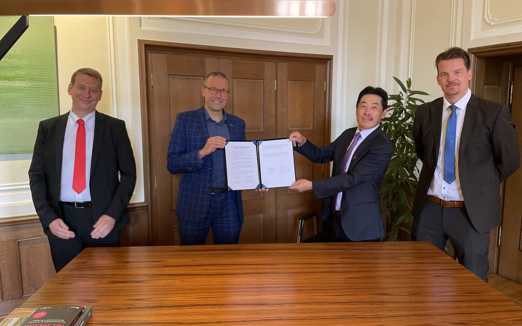  Von links: Christian Baierl, Oberbürgermeister Uwe Schneidewind, Tao Jiang und Hanno Rademacher  präsentieren das unterschriebene Abkommen zur zukünftigen Kooperation mit China bei Klimaschutz-Themen. 
