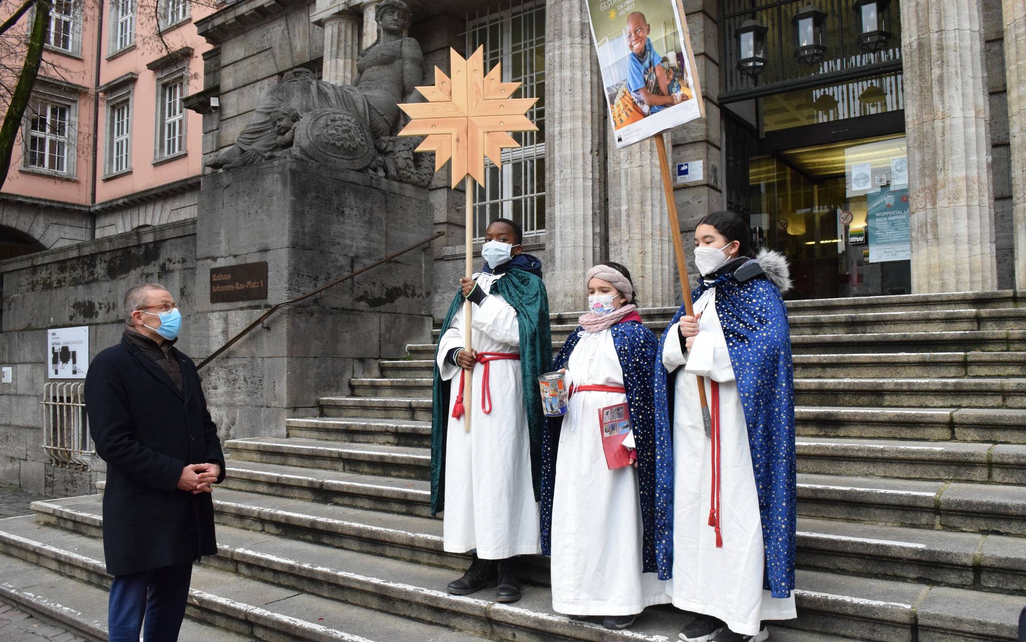  Oberbürgermeister Uwe Schneidewind mit drei Sternsingerinnen und singern der Gemeinde St. Antonius vor dem Rathaus. 