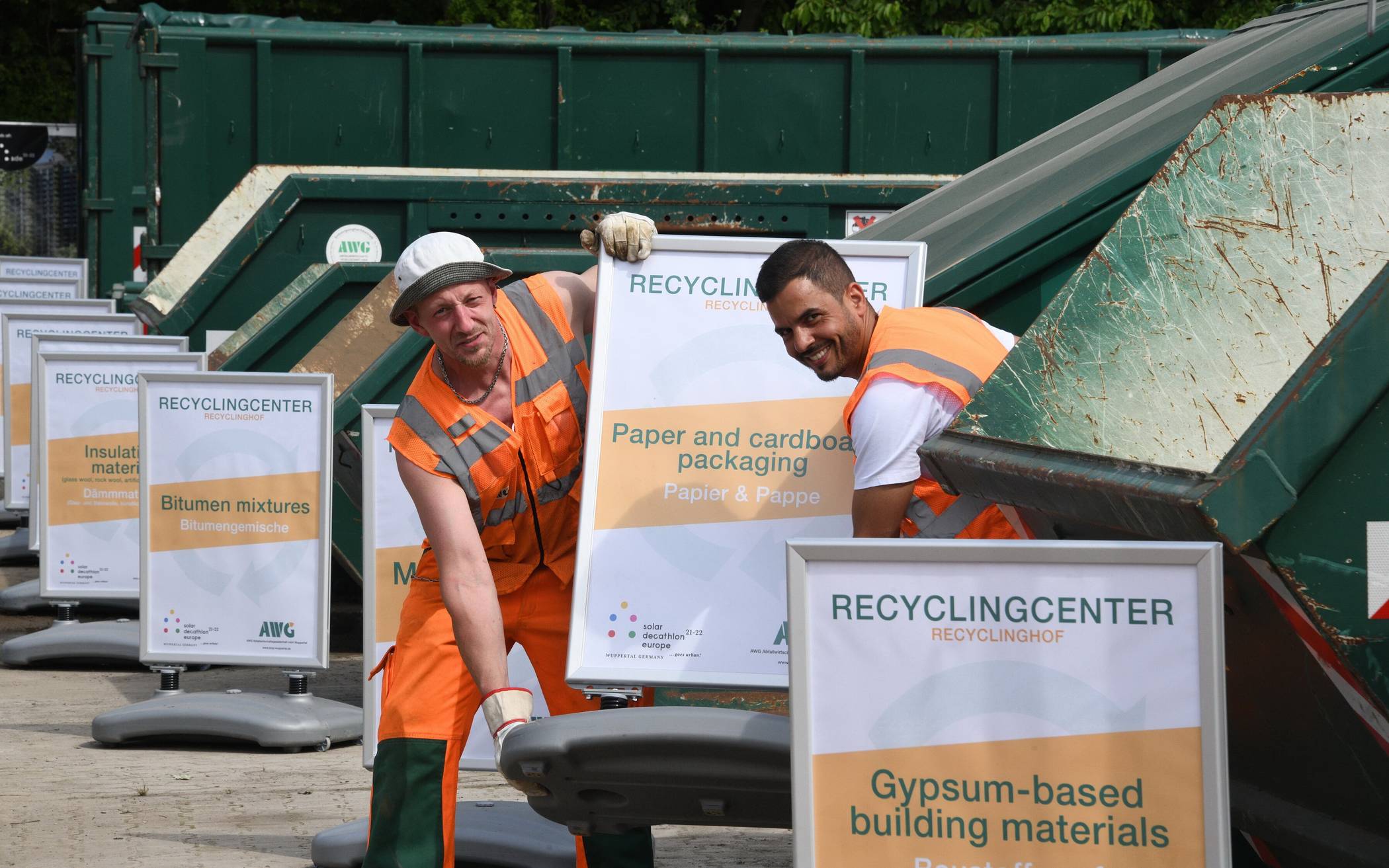  AWG-Mitarbeiter haben während der Bauphase des Solar Decathlon 2022 auf dem AWG-Recyclingcenter zweisprachige Hinweisschilder für die Mülltrennung aufgestellt. 