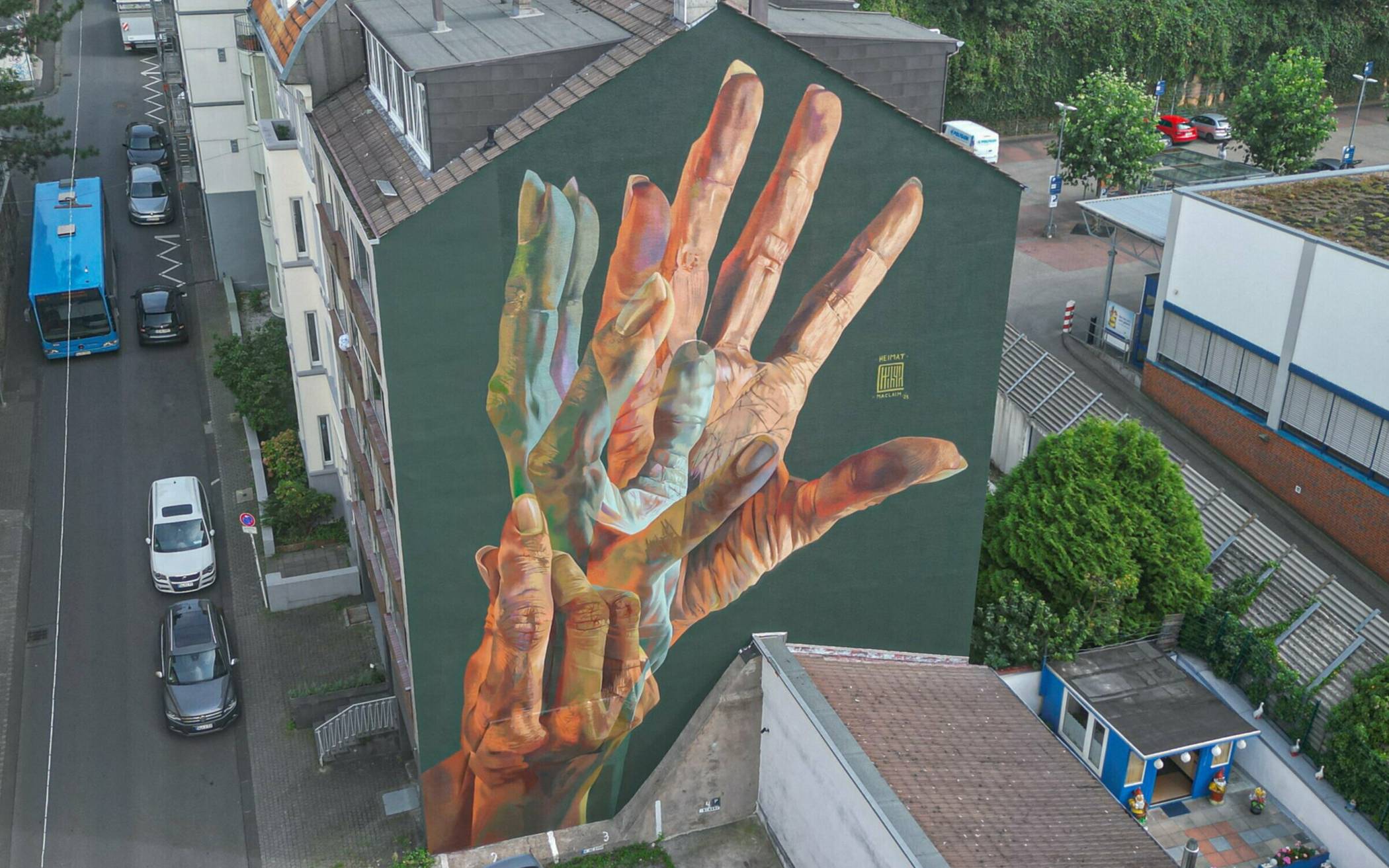  An der Schlieperstraße 21 zwischen Hofkamp und Hardt hat der international bekannte Street-Art-Künstler Case Maclaim aus Frankfurt auf beeindruckende Weise mit drei gemalten Händen den Begriff „Heimat“ als Gebärde gestaltet.  