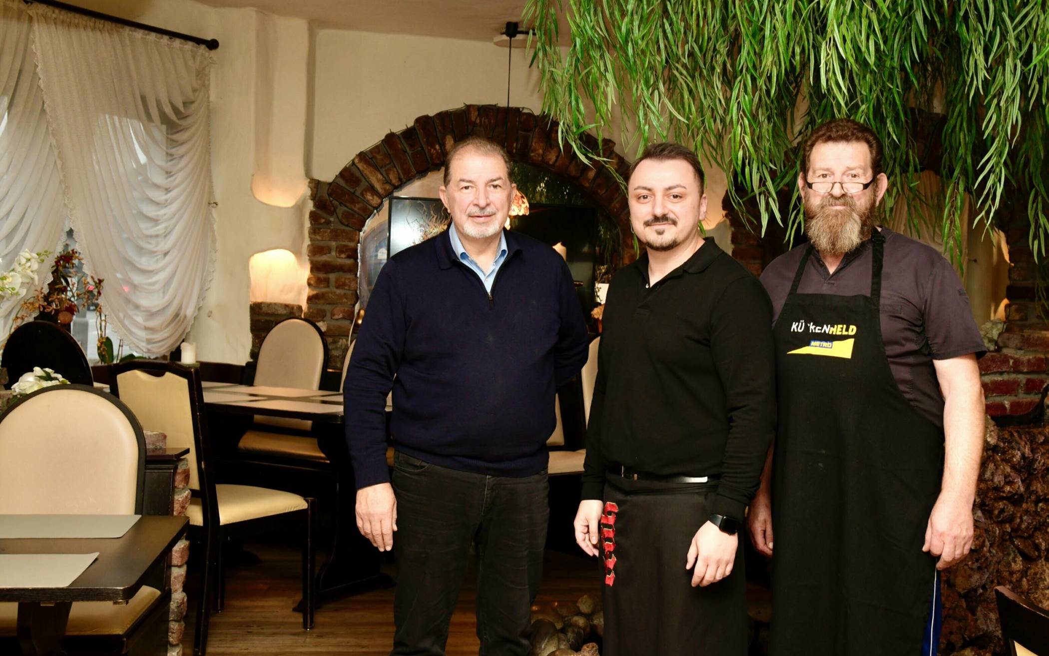   Kosta Gouziotis (links) hat das Restauran Samos an seinen langjährigen Mitarbeiter Stefanos Christodoulidis (Mitte) übergeben. Ansonsten bleibt im Traditionslokal alles wie gehabt – und am Herd steht weiterhin Mike Gouziotis (rechts).      