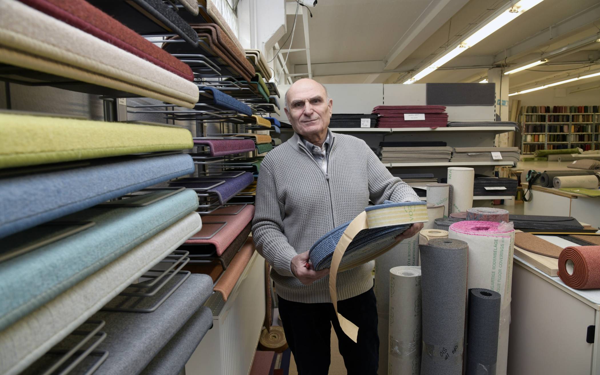 Georgios Paridis zeigt eine Rolle mit selbstklebenden und umkettelten Teppichsockelleisten, die in seiner Firma angefertigt werden.