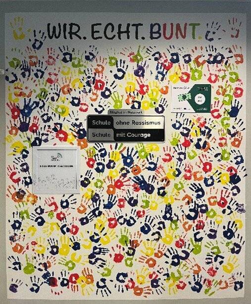  Unter dem Motto „Wir. Echt. Bunt.” organisierte der Anti-Rassismus-Arbeitskreis der Gesamtschule Uellendahl-Katernberg eine besondere Aktion, um ein Zeichen für Vielfalt und Zusammenhalt zu setzen. Schülerinnen und Schüler, Lehrkräfte und Mitarbeitende hinterließen ihre farbigen Handabdrücke auf einer großen Wand – als Symbol für eine Schule ohne Ausgrenzung und Diskriminierung. Ein weiteres Zeichen setzte die Schülervertretung (SV) gemeinsam mit dem Elterncafé mit einem gemeinsamen Fastenbrechen. 
