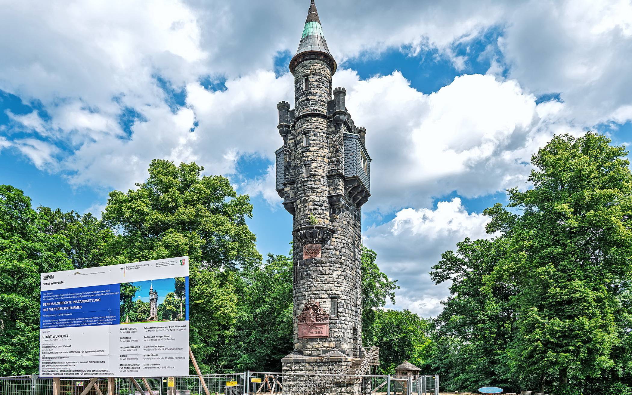 Der Zaun und das Bauschild stehen