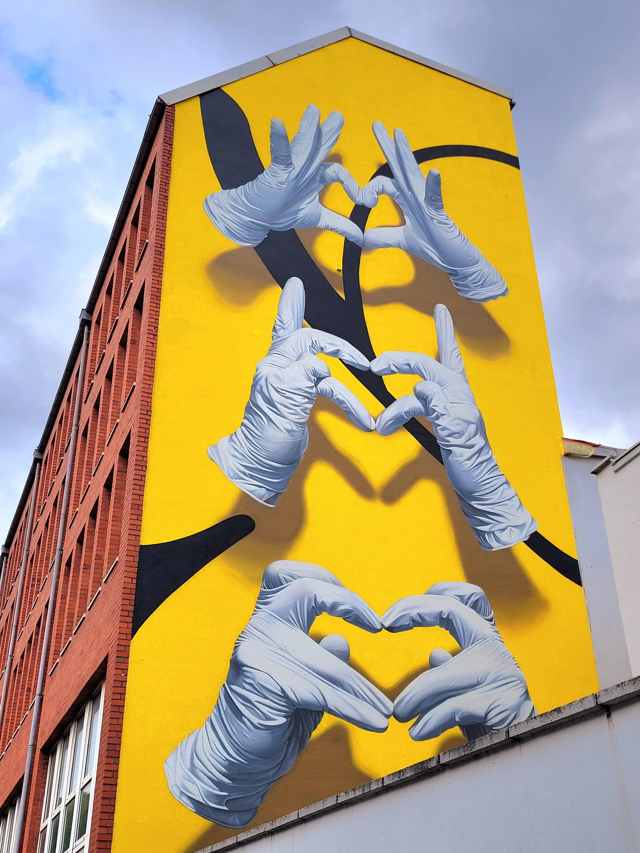 Drei Herz-Hände auf gelbem Grund von Nuno Viegas aus Portugal an der Rudolfstraße...