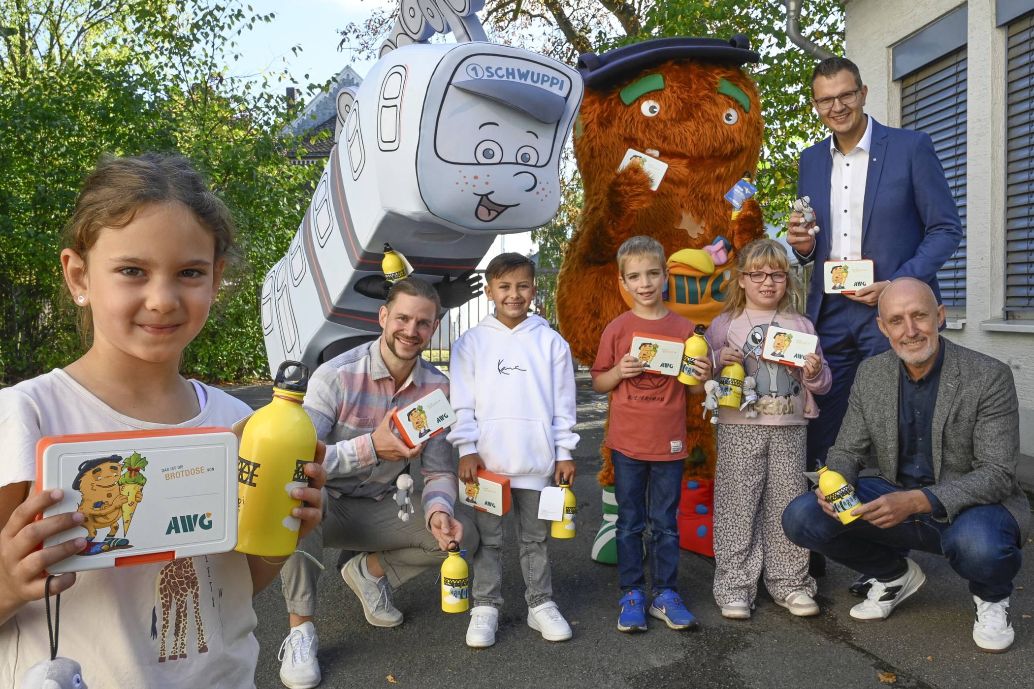  Auf dem Schulhof der GGS Hottenstein mit dem Schwebebahn-Maskottchen Schwuppi und dem AWG-Maskottchen Kalle (von li.): Erstklässlerin Hannah, Schulleiter Konstantin Konrad, Elian, Paul, Lea, Markus Schlomski (Arbeitsdirektor und Vorstand der WSW Energie &amp; Wasser AG, vorne im Bild) und Sascha Grabowski (AWG-Geschäftsführer und ESW-Betriebsleiter).  