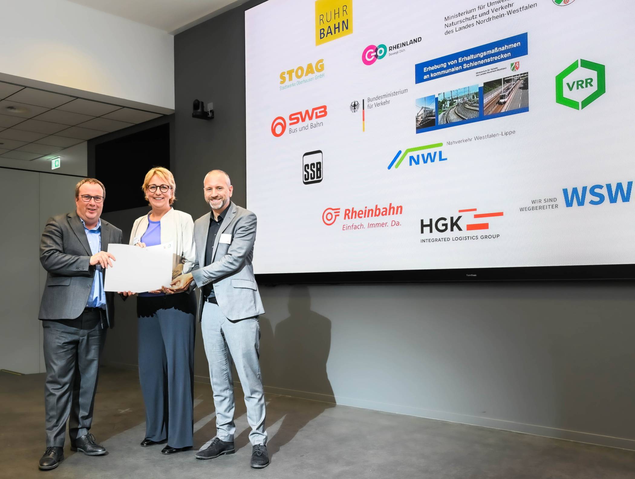  Von li.: Umwelt- und Verkehrsminister Oliver Krischer, Sabine Schnake (Geschäftsführerin WSW mobil GmbH) und Marc Nüßen (Abteilungsleiter Fördermanagement und Infrastrukturentwicklung VRR) bei der Übergabe des Förderbescheids. 