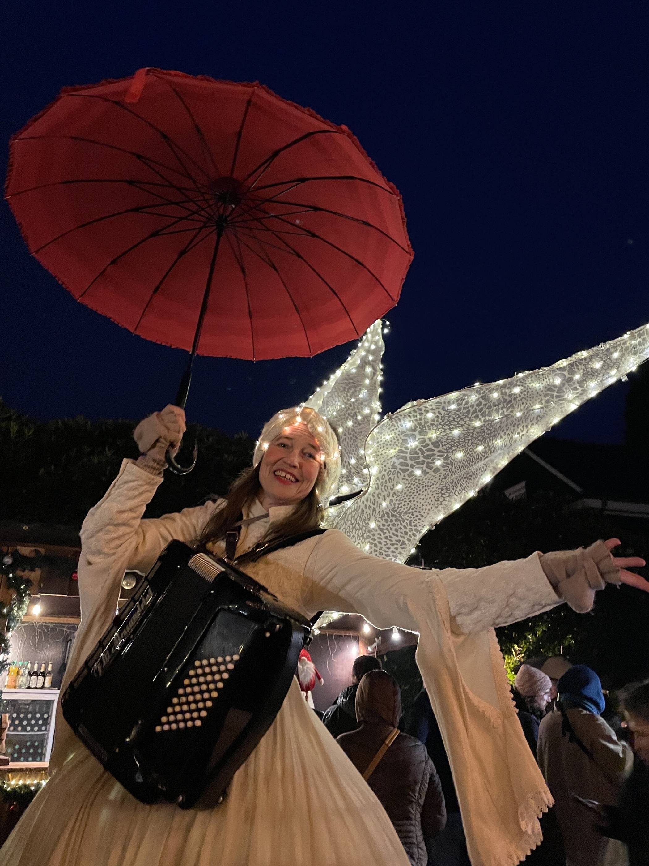Ein Engel auf Stelzen spielt Akkordeon und sorgt mit seinem Auftritt für fröhliche...