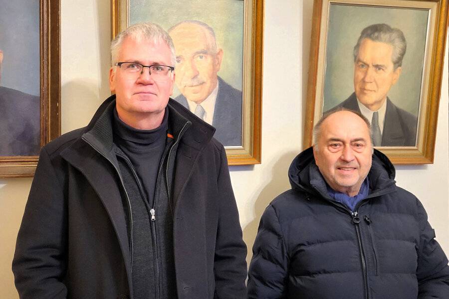 Gernold Sommer und Frank Römpke vor den Bildern der pensionierten Pfarrer in der Sakristei.