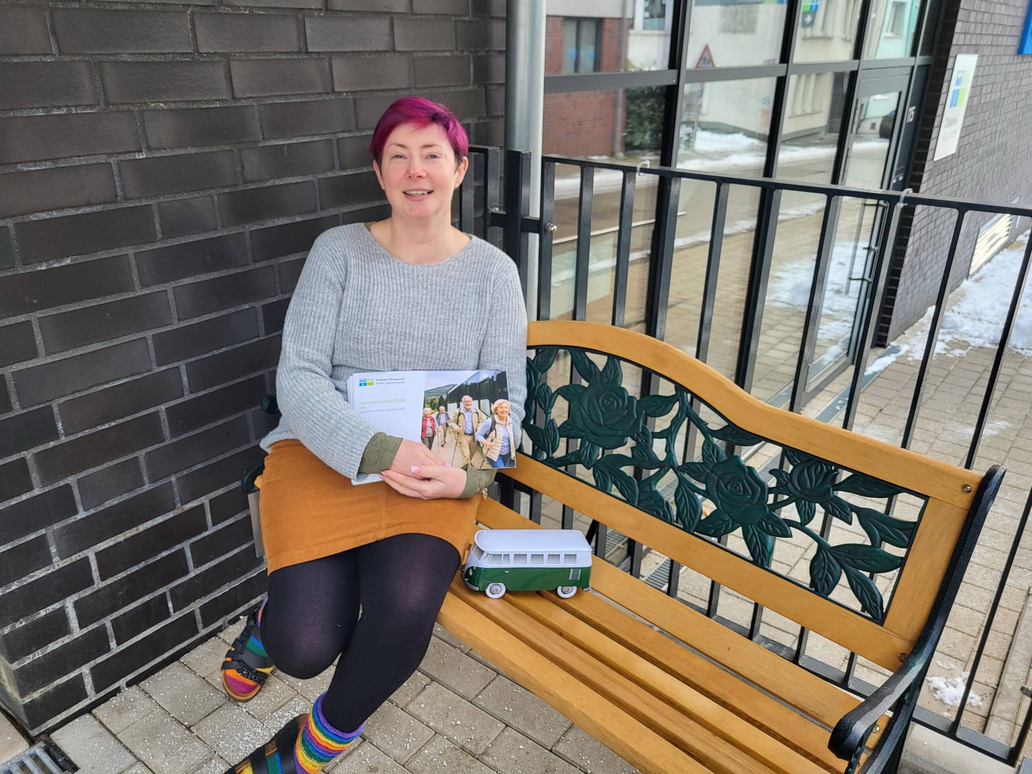 Melanie Hölter auf der Bank vor der Zentrale der Diakonie Wuppertal mit dem aktuellen Katalog.