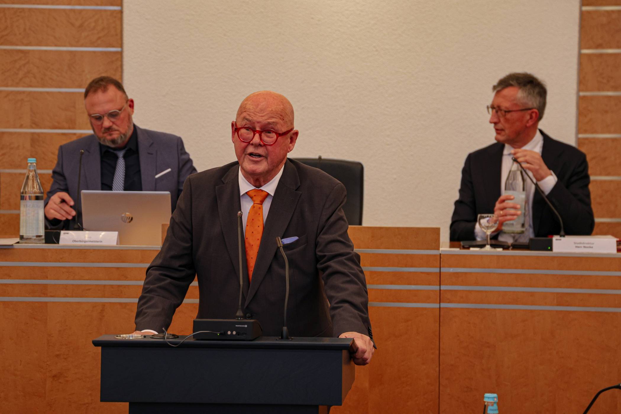  Dr. Rolf Köster am Rednerpult im Stadtrat. Hinten rechts der Beigeordnete Matthias Nocke. 