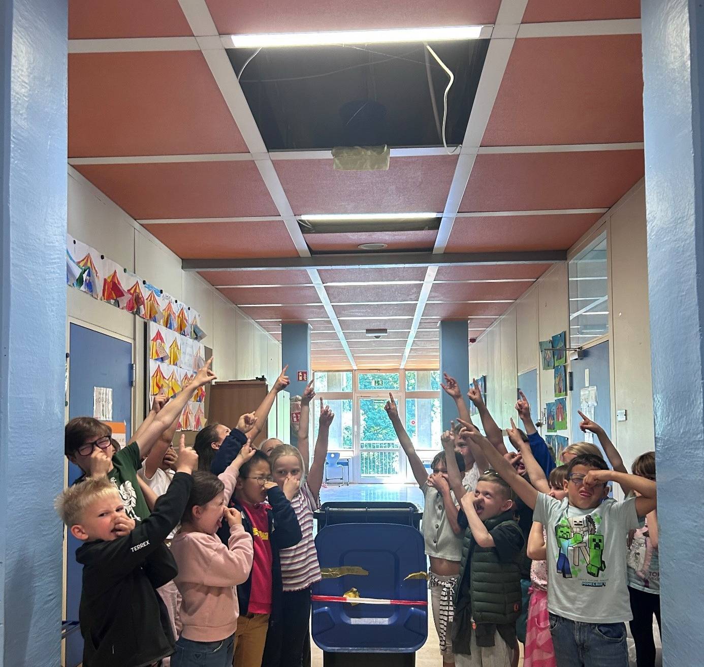  Die Grundschülerinnen und -schüler weisen auf auf die marode Decke. 