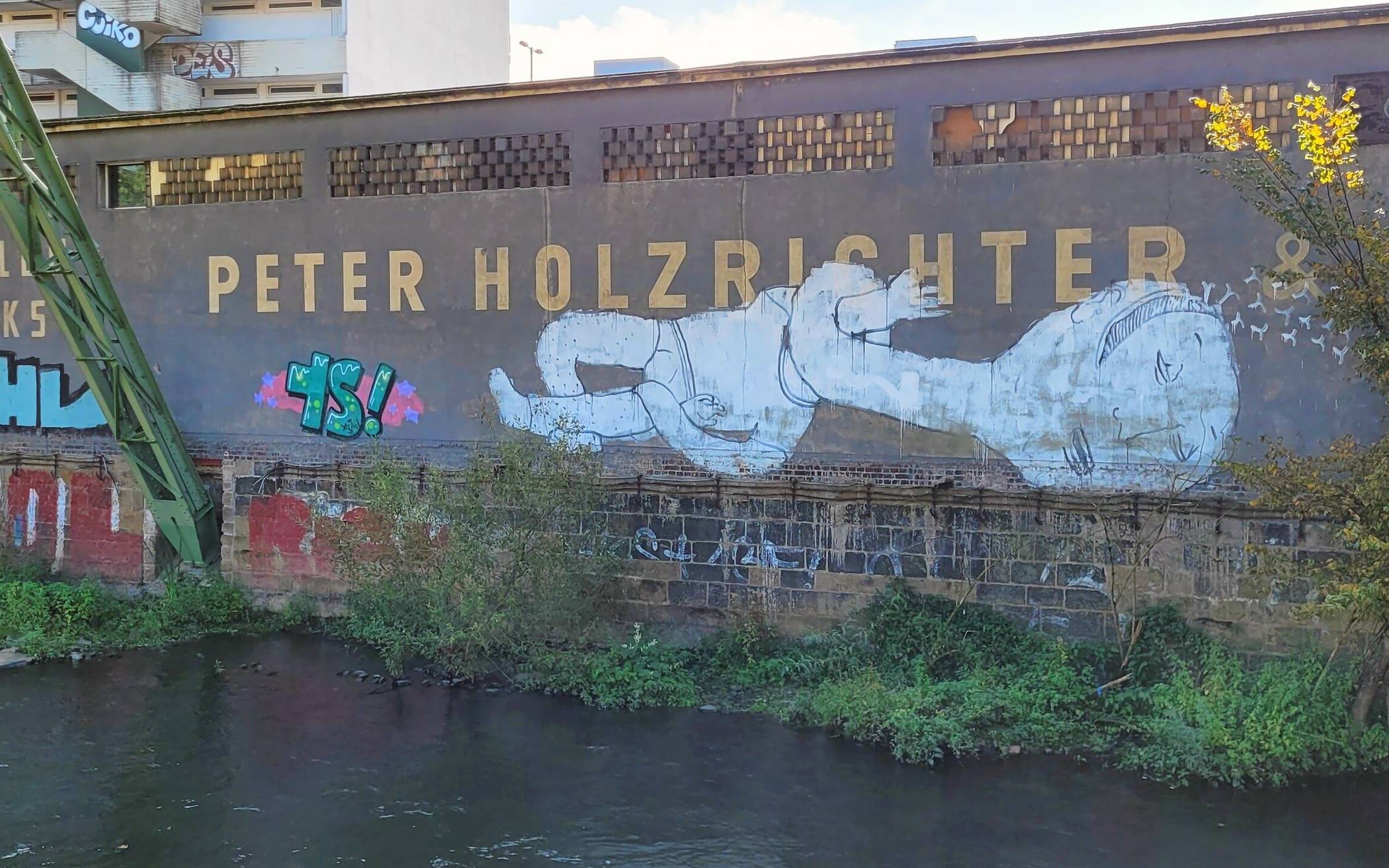 Erinnert an das Street-Art-Projekt "Outsides" des Sommers 2006: An der Wupperufermauer gegenüber der Gesamtschule Barmen am Unterdörnen hierließ der italienische Street-Artist „Blu“ ein für seinen Stil sehr typisches weißes Wesen. Diese Arbeit hat die vergangenen zwei Jahrzehnte überdauert.
