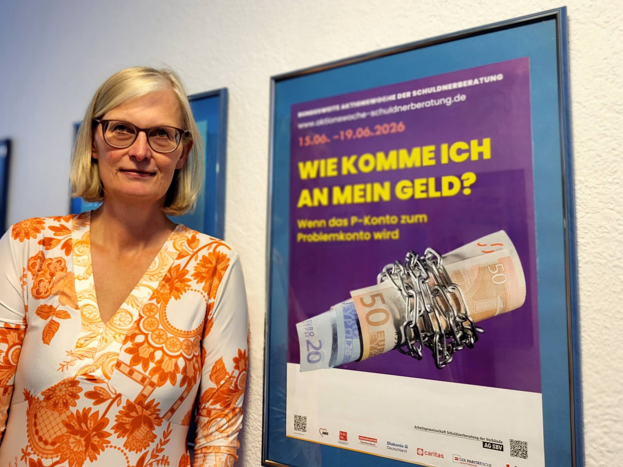 Anke Lichte (Leiterin der Schuldner- und Insolvenzberatung der Diakonie Wuppertal) vor dem Plakat der Aktionswoche.