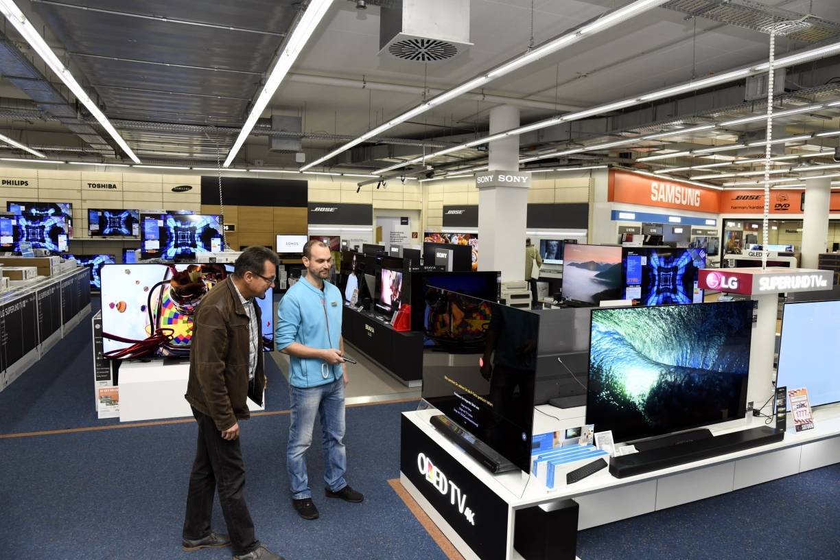  Saturn-Mitarbeiter Andre Heinicke kennt sich aus und berät einen Kunden zu Vorteilen und Möglichkeiten eines Flatscreen-TVs.  