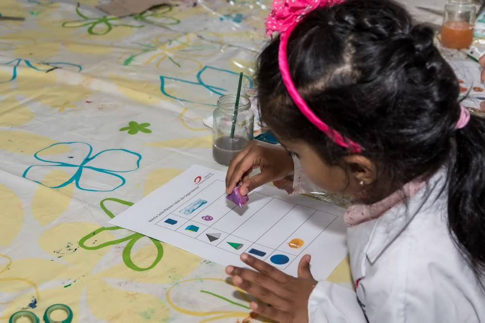  Eine junge Studentin erarbeitet sich mit einem Stempel verschiedene geometrische Formen.  