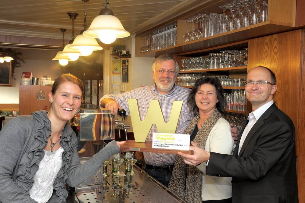  „So schmeckt Wuppertal!“-Medienberaterin Stefanie Pöller (li.) und Rundschau-Geschäftsführer Lutz Rensch (re.) überraschten Barbara und Harald Nolzen mit dem „Goldenen W“. 