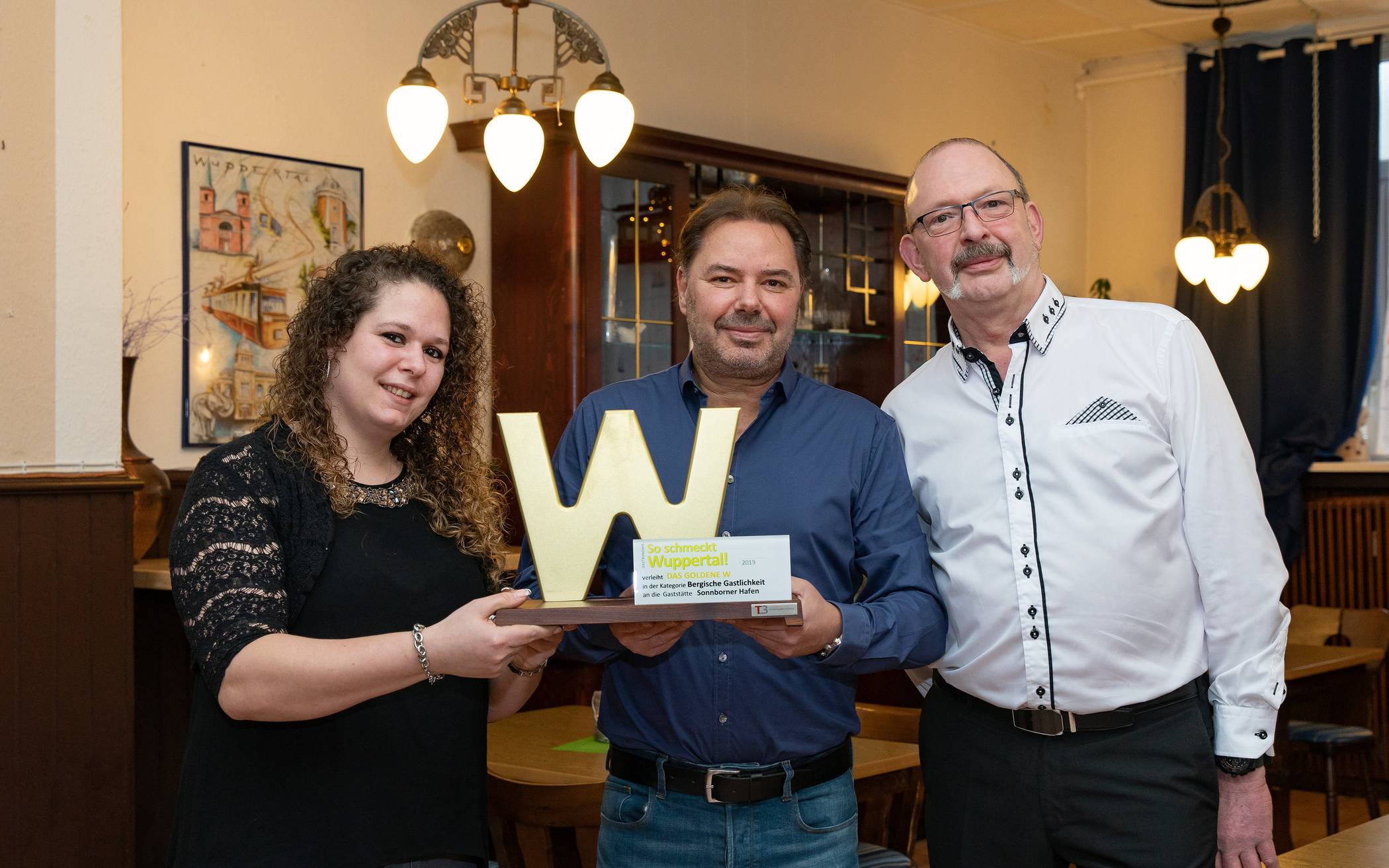  Rundschau-Redaktionsleiter Roderich Trapp (Mitte) gratuliert dem Team des Sonnborner Hafens zum „Goldenen W“. 